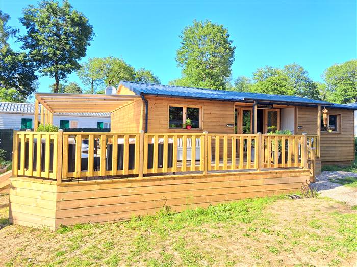 Le Chalet Terrasse Panoramique — Un chalet en bois chaleureux et une immense terrasse panoramique sous les arbres.