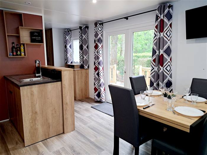 Le Cottage Panoramique — En pleine forêt, une pièce de vie lumineuse avec vue sur les arbres.